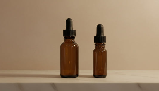 Two brown glass dropper bottles with black caps on a beige background